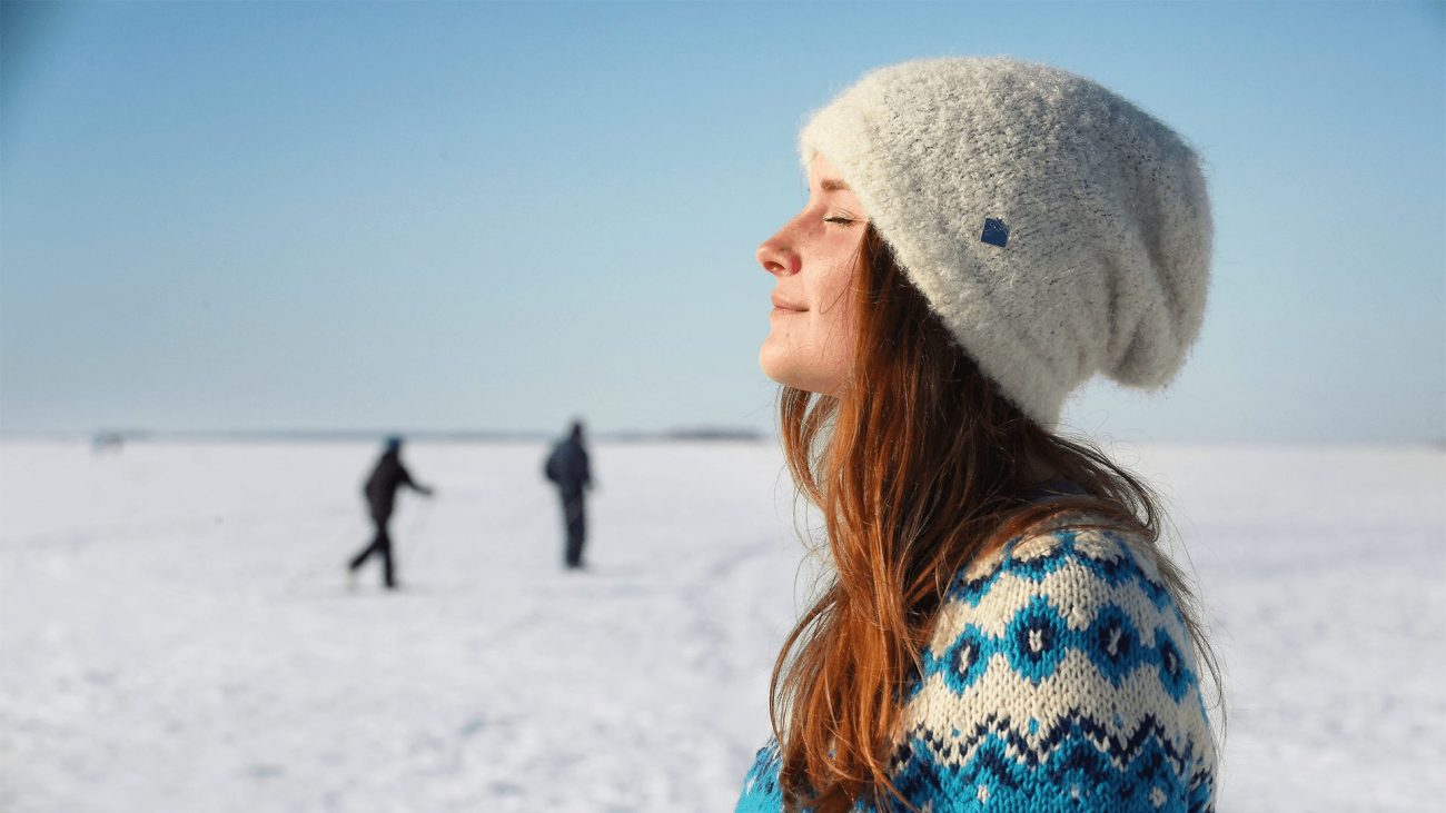 Eine Frau genießt die Sonne im finnischen Winter. 
