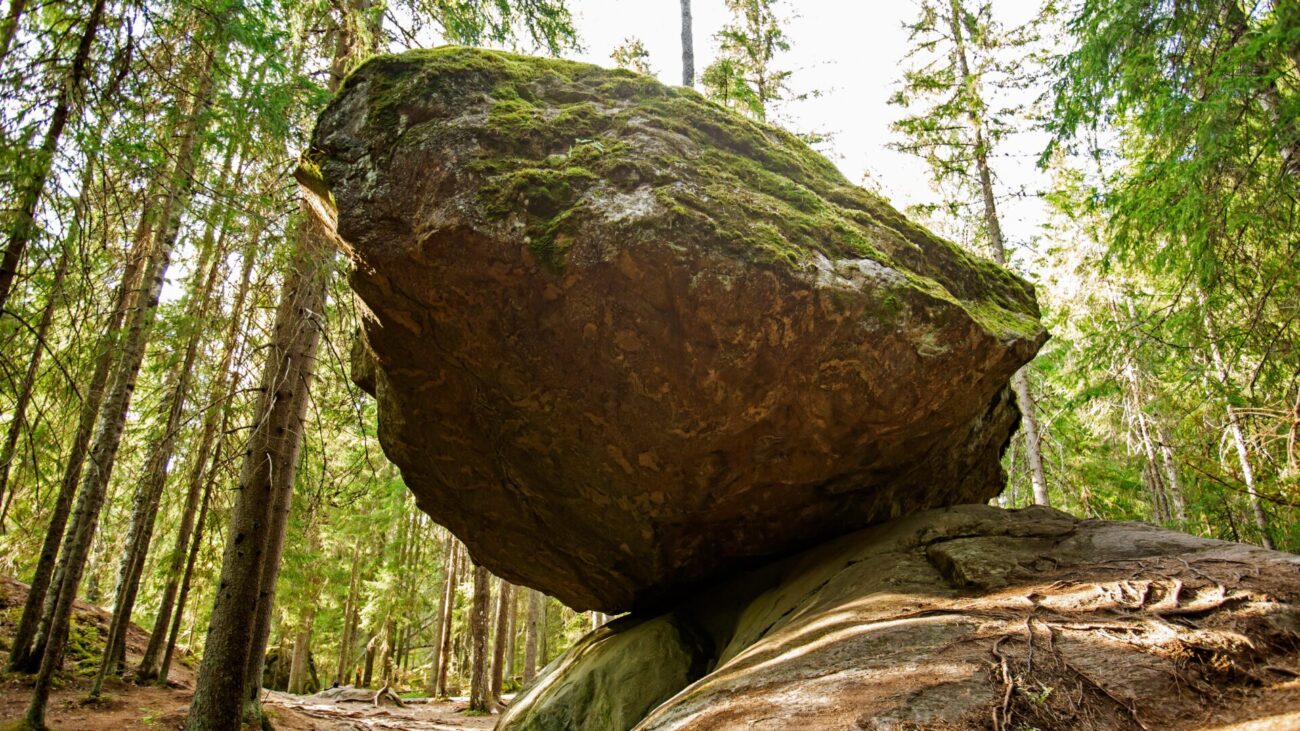 Findling im Wald balanciert auf kleinerem Stein in der finnischen Natur. 