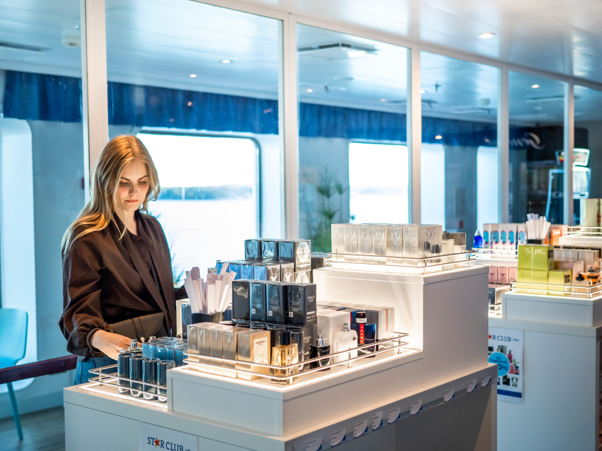 Vrouw snuffelt in de boordwinkel door de parfumselectie.