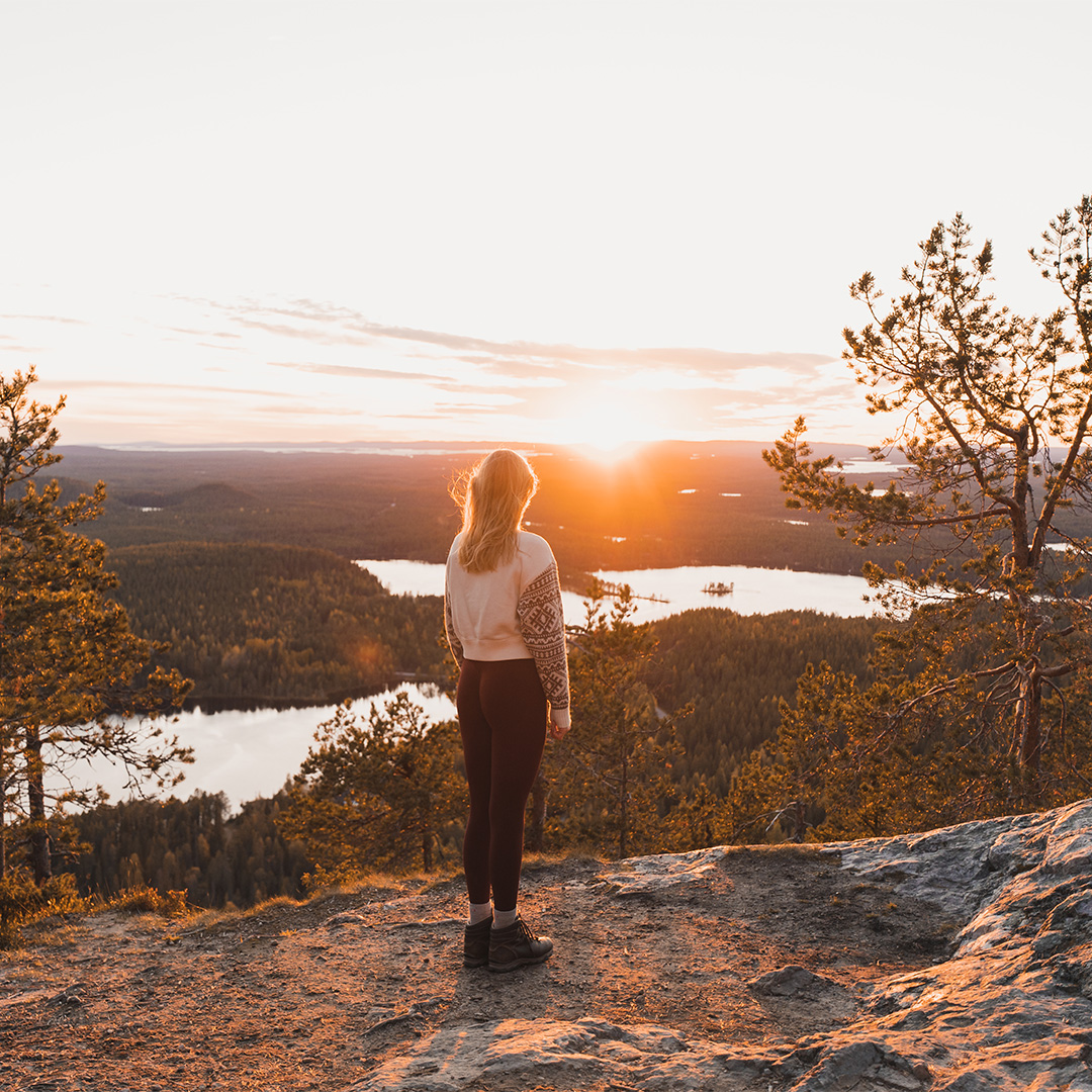 Frau blickt auf Seen und Wälder in Finnland im Herbst
