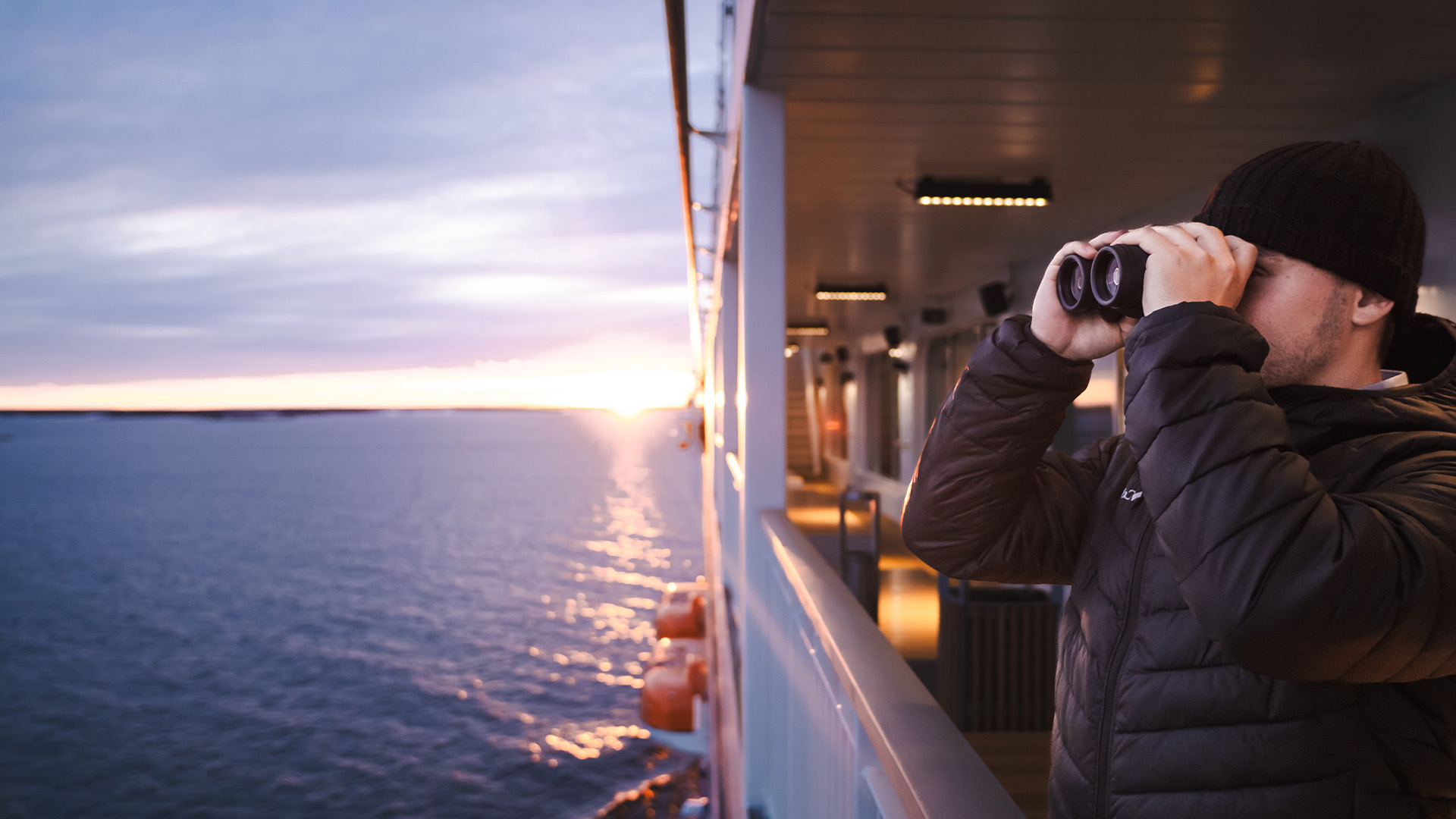 Man met een verrekijker aan boord van een veerboot.