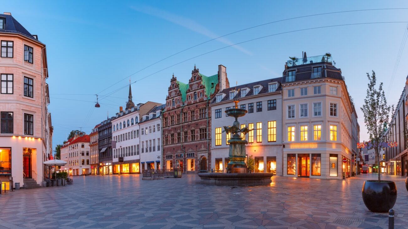 Plac z fontanną pośrodku wyrafinowanej ulicy handlowej Strøget w Kopenhadze.