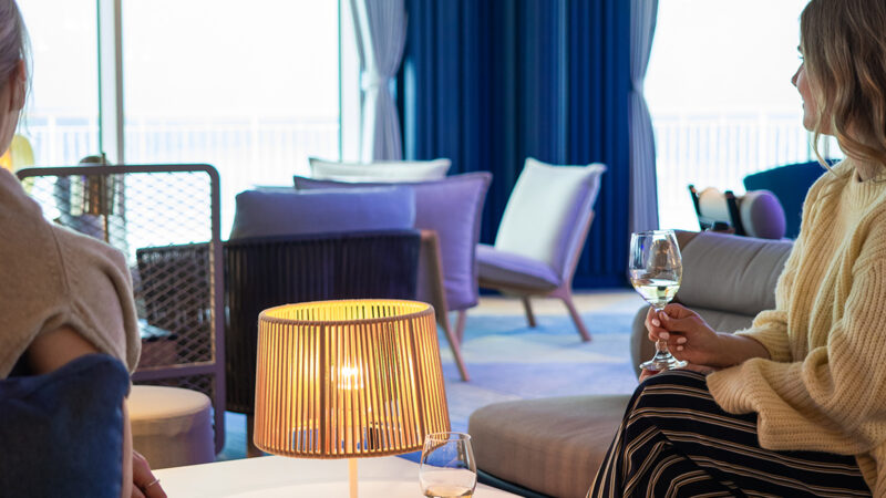Bild på två tjejer som sitter med varsitt glas vin i Premium Stellar Lounge ombord på Finnsirius.