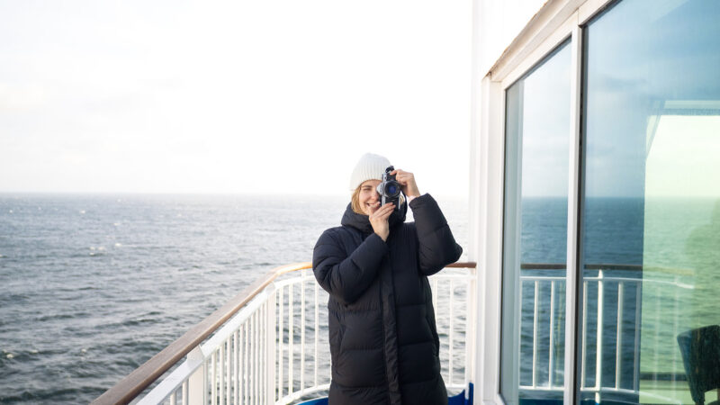 Bild på en tjej som står och fotograferar med en kamera ombord på Finnlines färja. 