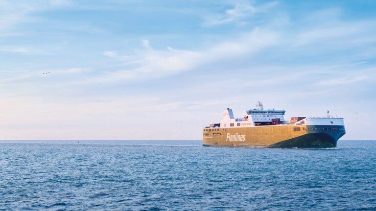 Finnlines RoRo vessel of the Eco class sailing in open sea under a bright blue sky with wispy clouds