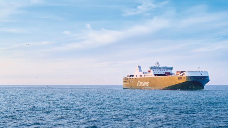 Finnlines RoRo vessel of the Eco class sailing in open sea under a bright blue sky with wispy clouds