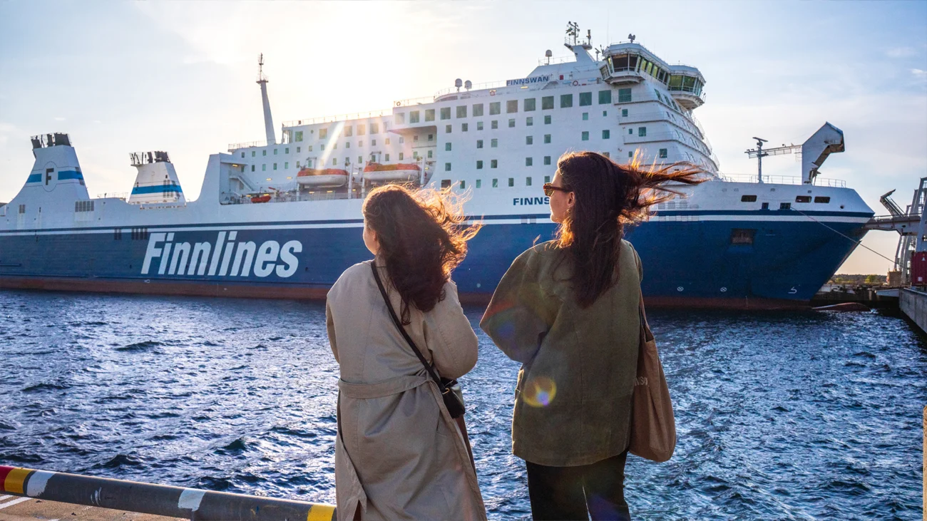 Zwei Frauen stehen am Hafen und blicken auf die Finnlines-Fähre.