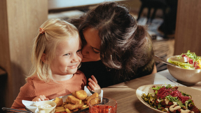 Bild på en liten flicka och sin mamma som pussar på henne, i Fishermans bistro och äter middag.